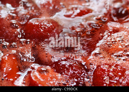 Nahaufnahme von Erdbeermarmelade wird in Edelstahl-Pfanne gekocht Stockfoto
