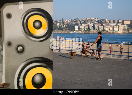 Ein Mann geht seinen Hunden durch Skateboard am Bondi Beach.  Sydney, New South Wales, Australien Stockfoto