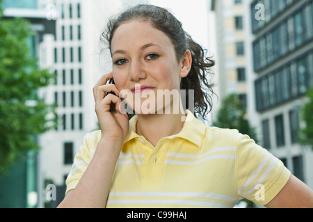 Deutschland, Berlin, Teenage Mädchen mit Handy in Stadt, Lächeln Stockfoto