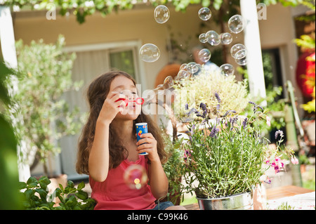 Deutschland, Bayern, Mädchen bläst Seifenblasen im Garten Stockfoto