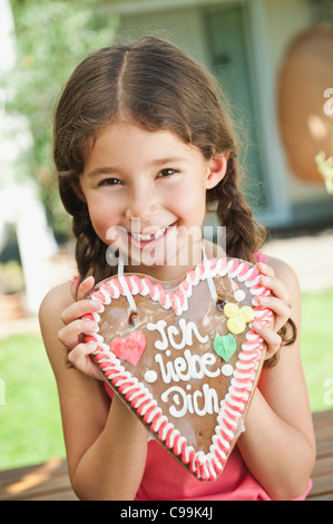 Deutschland, Bayern, Mädchen mit Lebkuchenherz, Lächeln, Porträt Stockfoto