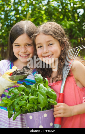 Deutschland, Bayern, Schwestern tun Gartenarbeit im Garten, Lächeln, Porträt Stockfoto