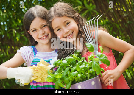 Deutschland, Bayern, Schwestern tun Gartenarbeit im Garten, Lächeln, Porträt Stockfoto