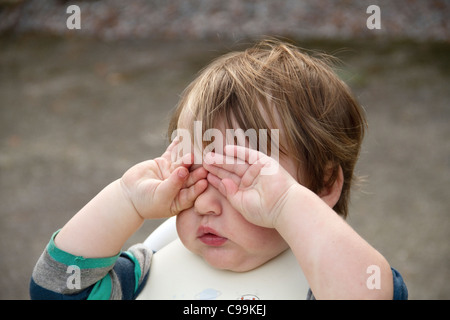 Sehr müde Kleinkind reibt die Augen außerhalb nach Essen Stockfoto