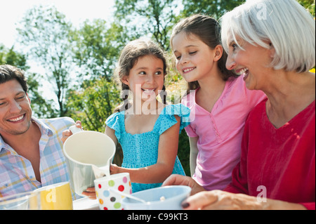 Deutschland, Bayern, Familie mit Kaffee und Kuchen im Garten, Lächeln Stockfoto