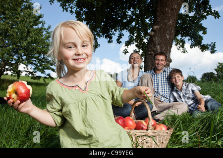Deutschland, Bayern, Altenthann, Mädchen mit Korb Äpfel, Familie mit Hund im Hintergrund Stockfoto