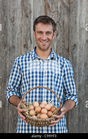 Deutschland, Bayern, Altenthann, Mann hält Korb mit Eiern, Lächeln, Porträt Stockfoto