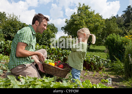 Deutschland, Bayern, Altenthann, Vater und Tochter halten Korb voll mit Gemüse Stockfoto