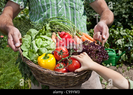 Deutschland, Bayern, Altenthann, Vater und Tochter halten Korb voll mit Gemüse Stockfoto