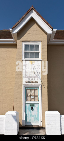 Verblasste blau lackierten Haustür mit einer Sonnenuhr darüber, dann ein Schiebefenster und ein Satteldach Stockfoto