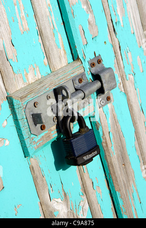 Riegel und Vorhängeschloss am Strand Hütte Tür. Holz und blauer Farbe verblasst Stockfoto