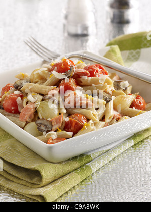 Eine Schüssel mit geräuchertem Lachs Pasta mit Tomaten, Perlzwiebeln und Champignons in einer Sahnesauce und garniert mit Parmesan-Käse Stockfoto