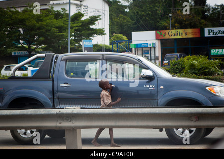 Eine Straße Kind in Mombasa, Kenia betteln um Geld von einem weißen Mann vorbeifahren. Stockfoto