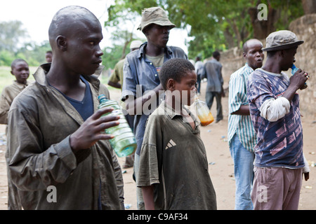 Mombasa, Kenia. Junge Männer hoch auf dem Leim. Die Straßengang Kinder und junge Männer sind offen Klebstoffschnüffeln und Spannungen hoch laufen. Stockfoto