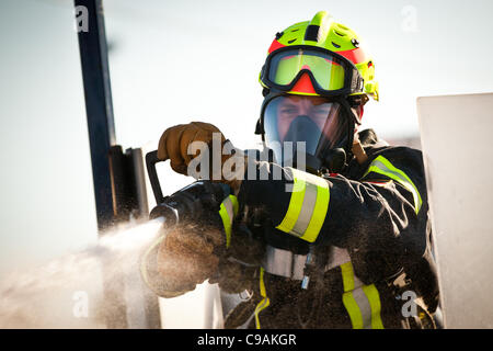 Ein Feuerwehrmann soll ein Feuerwehrschlauch auf ein Ziel beim vollen Brandbekämpfung Ausrüstung tragen und arbeiten gegen die Zeit während das internationale Finale des Firefighter Combat Challenge am 18. November 2011 in Myrtle Beach, South Carolina. Stockfoto