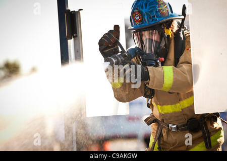 Ein Feuerwehrmann soll ein Feuerwehrschlauch auf ein Ziel beim vollen Brandbekämpfung Ausrüstung tragen und arbeiten gegen die Zeit während das internationale Finale des Firefighter Combat Challenge am 18. November 2011 in Myrtle Beach, South Carolina. Stockfoto