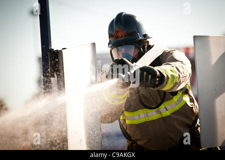 Ein Feuerwehrmann soll ein Feuerwehrschlauch auf ein Ziel beim vollen Brandbekämpfung Ausrüstung tragen und arbeiten gegen die Zeit während das internationale Finale des Firefighter Combat Challenge am 18. November 2011 in Myrtle Beach, South Carolina. Stockfoto