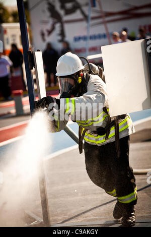 Ein Feuerwehrmann soll ein Feuerwehrschlauch auf ein Ziel beim vollen Brandbekämpfung Ausrüstung tragen und arbeiten gegen die Zeit während das internationale Finale des Firefighter Combat Challenge am 18. November 2011 in Myrtle Beach, South Carolina. Stockfoto