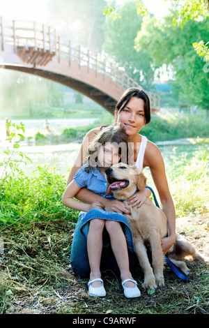 Tochter und Mutter mit golden Retriever Hund im Outdoorpark Stockfoto