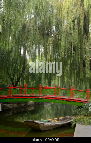 Alte Brücke mit Geländer und Boot mit grünen hängenden Willow Tree Blätter in changpu River Park Beijing China Stockfoto