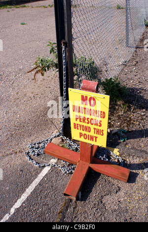 ein Schild mit der Aufschrift "keine unbefugten Persons über diesen Punkt hinaus" angekettet an einem Drahtzaun. Stockfoto