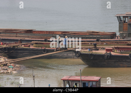 Zwei Männer mit Carying Pole, Müll auf einer Barke an Chizhou, China zu laden Stockfoto
