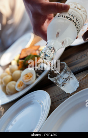 Ein Glas Koskenkorva Viina (auch bekannt einfach als verarbeitet oder Kossu) Gießen in ein Glas Stockfoto