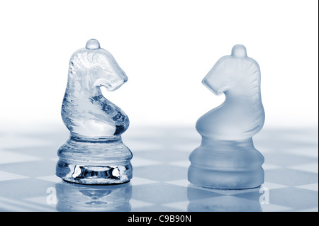 Zwei Glas-Schach-Pferde. Blau getönt. Es ist auf einem weißen Hintergrund isoliert. Stockfoto