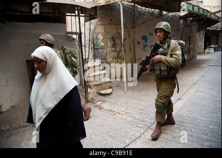 Israelische Soldaten patrouillieren unter palästinensischen Fußgänger in der Westbank-Stadt Hebron. Stockfoto