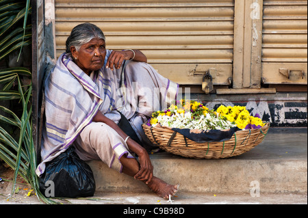 Indische Frau verkaufen Ringelblumen in einem Korb für hindu Puja-Angebote Stockfoto