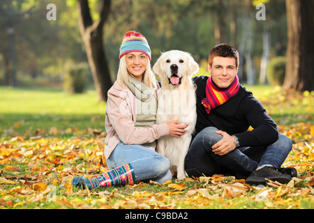 Lächelnde junge Mann und Frau umarmt einen Labrador Retriever Hund heraus Stockfoto