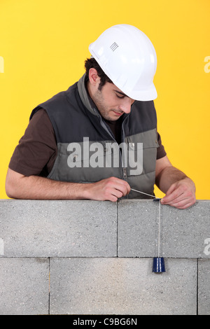 Ein Maurer mit einem Senklot, um seine Wand zu überprüfen. Stockfoto