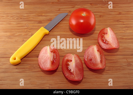 Tomaten und vier Tomaten Vierteln auf ein Schneidebrett Stockfoto