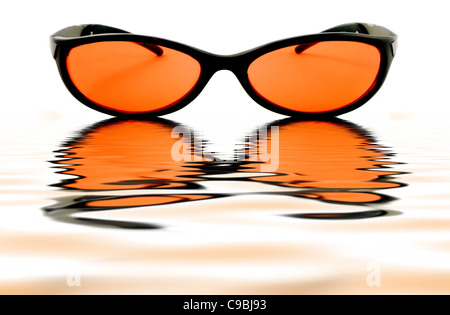 Orange Sonnenbrille spiegelt in einer Lache des Wassers auf einem weißen Hintergrund isoliert Stockfoto