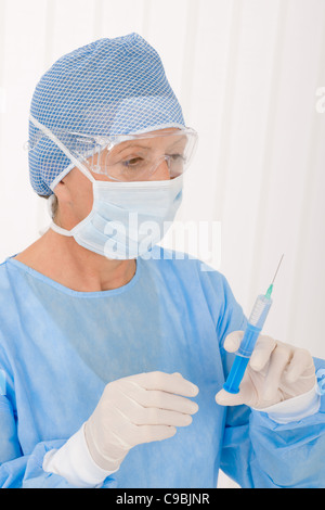 Leitender Chirurg weiblich halten Sie die Spritze im Schutzbetrieb einheitliche Maske Stockfoto
