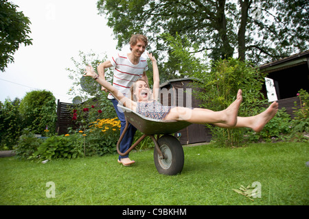 Mann schob Schubkarre mit Frau drauf liegen Stockfoto