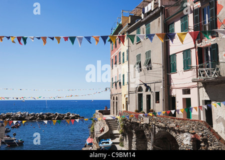 Italien, Ligurien, Cinque Terre, Riomaggiore Dorf Gebäude mit Girlanden und Meer im Hintergrund Stockfoto