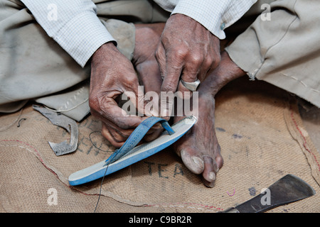 Mann, Reparatur von Schuhen auf der Straße im Dorf Sarod, Bundesstaat Gujarat, Indien. Stockfoto