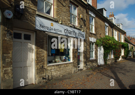 Der High Street in Olney mit einer Barmherzigkeit In Aktion-Charity-Shop im Vordergrund. Stockfoto