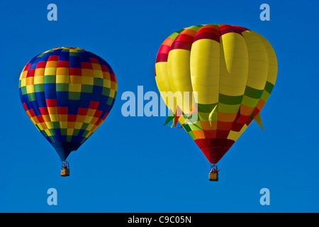 USA, New Mexico, Albuquerque, Ballon-Festival. Zwei bunte Heißluftballons in einem klaren blauen Himmel. Stockfoto