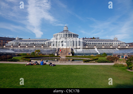 Menschen genießen die Sonne auf dem Rasen rund um das Gewächshaus im Botanischen Garten in Kopenhagen, Dänemark, an einem Herbsttag Stockfoto