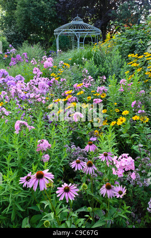 Purple cone Flower (Echinacea purpurea), Garten Phlox (Phlox paniculata) und false Sunflower (heliopsis helianthoides) vor einem Gartenpavillon. Stockfoto