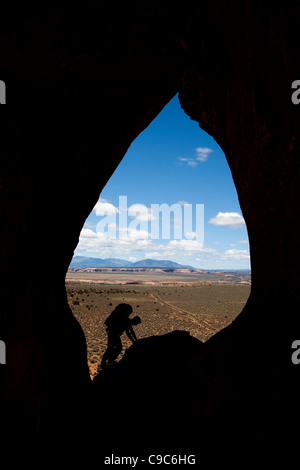 Kletterer stand im Spiegel Fenster Felsbogen in der Nähe von Moab in Utah USA Silhouette gegen die Wüste und die Berge Sanpete Stockfoto
