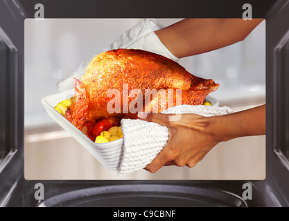 Hände der Frau ist Truthahn mit Kartoffeln aus dem Ofen herausnehmen Stockfoto