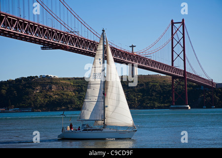 Segeln unter Pont 25 de Abril Brücke über den Fluss Tejo Lissabon Portugal Stockfoto