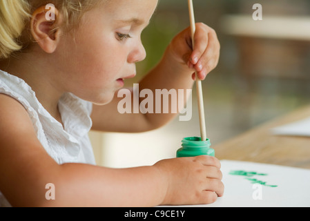 Kleines Mädchen Pinsel in Farbe getaucht Stockfoto