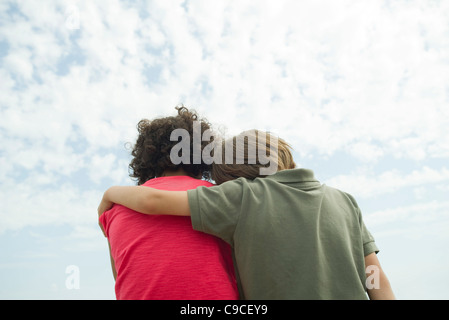 Junge Freunde sitzen nebeneinander im Freien, Rückansicht Stockfoto