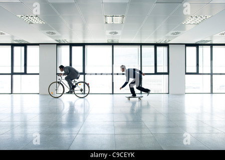 Ein Geschäftsmann mit Fahrrad, die anderen Skateboard Stockfoto