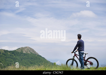 Mann stehend mit dem Mountainbike, malerischen Blick auf die Berge, Sicht nach hinten zu genießen Stockfoto