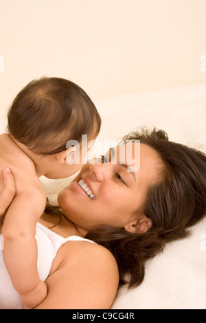 Mutter und Sohn auf Bett und Mutter umarmt die 5 Monate alten Säugling Baby mit ihm zu spielen Stockfoto